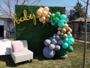 boxwood green wall, with balloon decor, andevent furniture