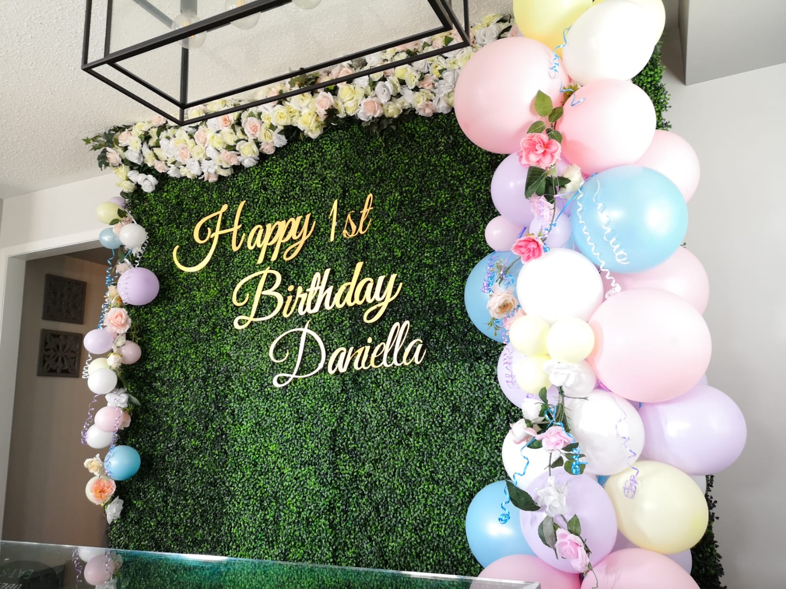 green boxwood wall with balloon garlands